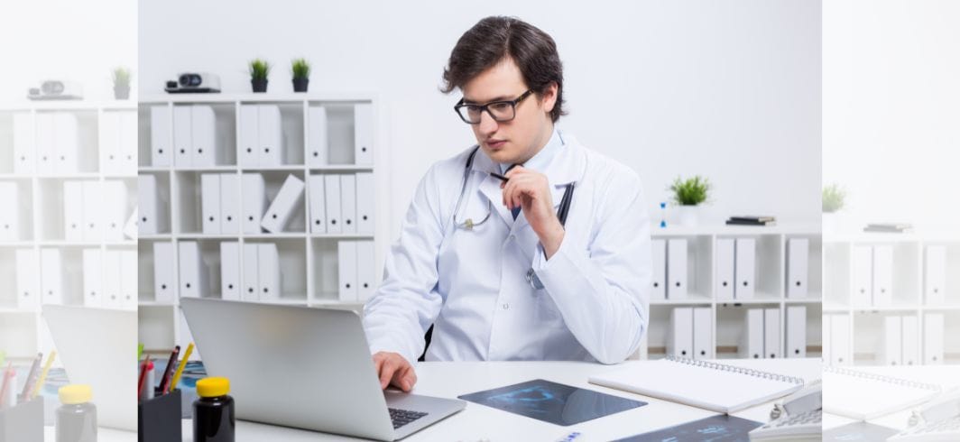 doctor sat at a desk on his laptop and x rays on his desk concept medical negligence pregnancy and birth injury stillbirth and neonatal medication errors hospital negligence client