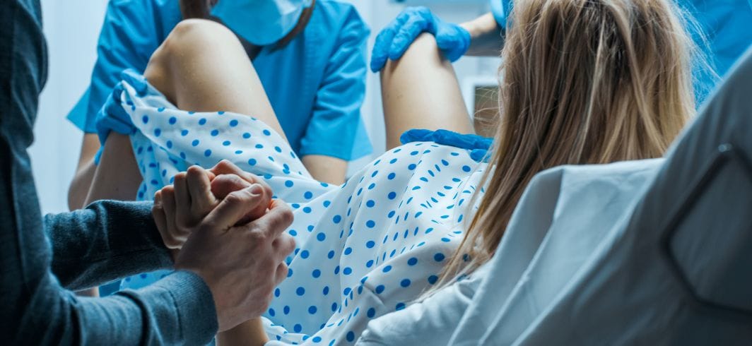 close up woman giving birth and holding hands with man concept representing medical negligence wrongful birth compensation claims