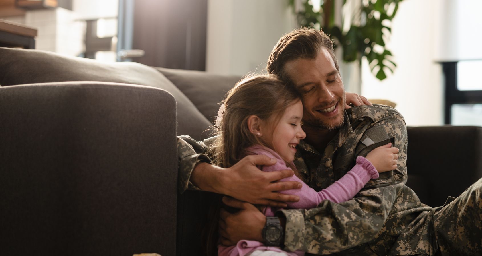 military man hugging daughter sat on the floor representing military compensation claims
