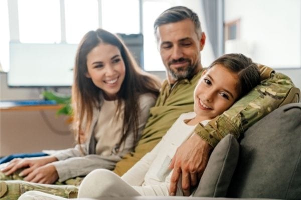 military-dad-with-family-sat-on-sofa-smiling-after-military-claims-compensation-600px-400px