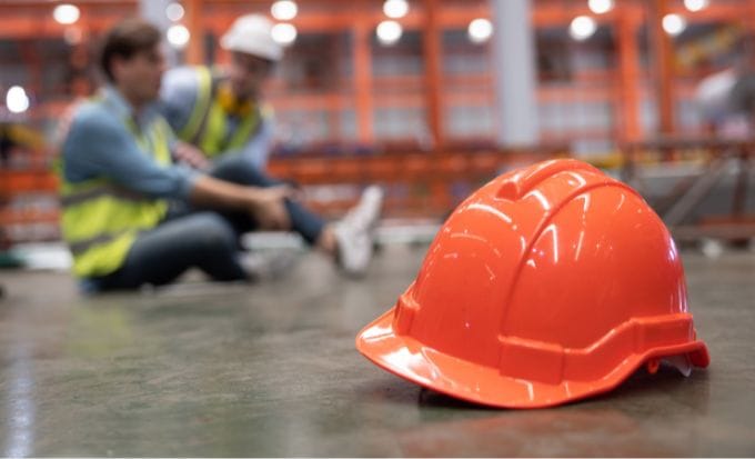 red hard hat with blurred injured factory workers as background concept personal injury workplace accidents