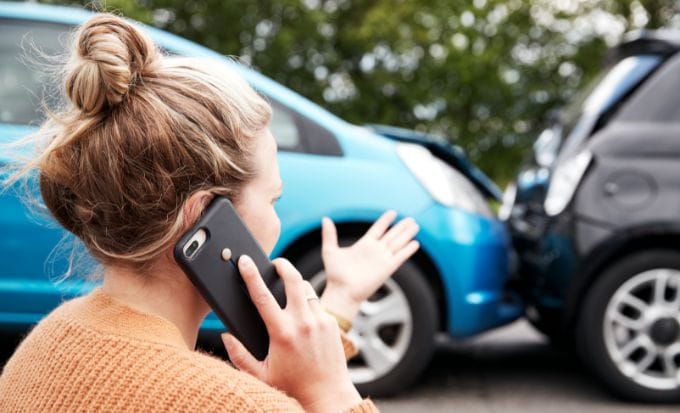 woman on her phone guesturing toward two cars that have crashed concept personal injury car passanger claims feature