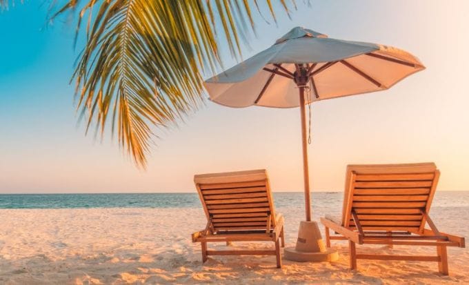 two sun loungers under an umbrella on the beach concept personal injury accidents abroad feature
