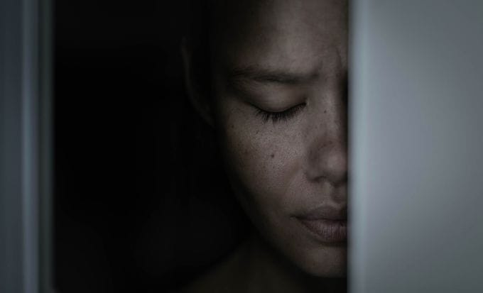 teenage girl leaning her head on a doorframe with her eyes closed concept criminal injury sexual abuse feature