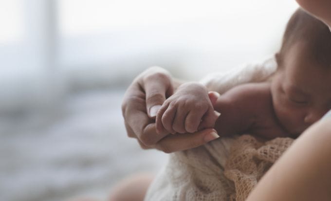 close up mother holding hands asian female newborn baby and sunlight in the morning concept representing medical negligence stillbirth and neonatal compensation claims feature