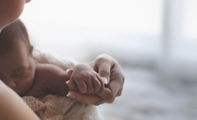 Close up Mother holding hands Asian female newborn baby and sunlight in the morning. Concept birth injury traumatic delivery.