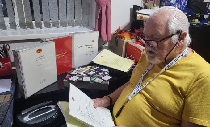 ken tooby looking through his wife’s files concept group actions post office capture it scandal feature