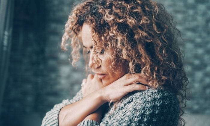 woman-long-hair-and-jumper-with-crossed-arms-over-holding-shoulders-concept-victim-of-criminal-injury-compensation-claims