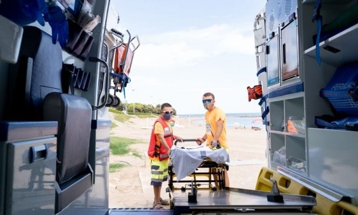ambulance and a team of first aid workers on beach concept representing accidents and injury abroad serious injury abroad compensation claims