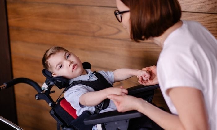 beautiful boy child in special wheelchair toddler with cerebral palsy with his mother concept representing medical negligence cerebral palsy compensation claims