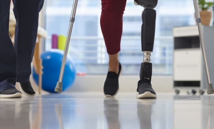 physiotherapist-and-woman-with-artificial-leg-walking-with-crutches-concept-representing-amputation-compensation-compensation-claims