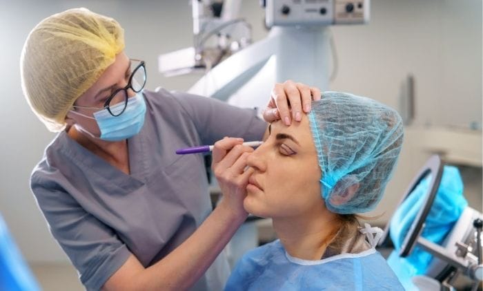 plastic surgeon applies markings to patient around eyes concept representing medical negligence cosmetic surgery compensation claims