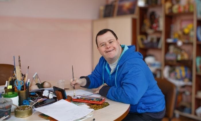 a man with down syndrome is engaged in drawing in a workshop concept court of protection deputyships statutory wills lasting power of attorney